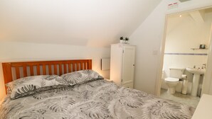 Un dormitorio con cama, armario, baño con inodoro y lavamanos, y techo con lámpara.