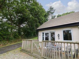 A house with a wooden deck, a paved path, and a garden.