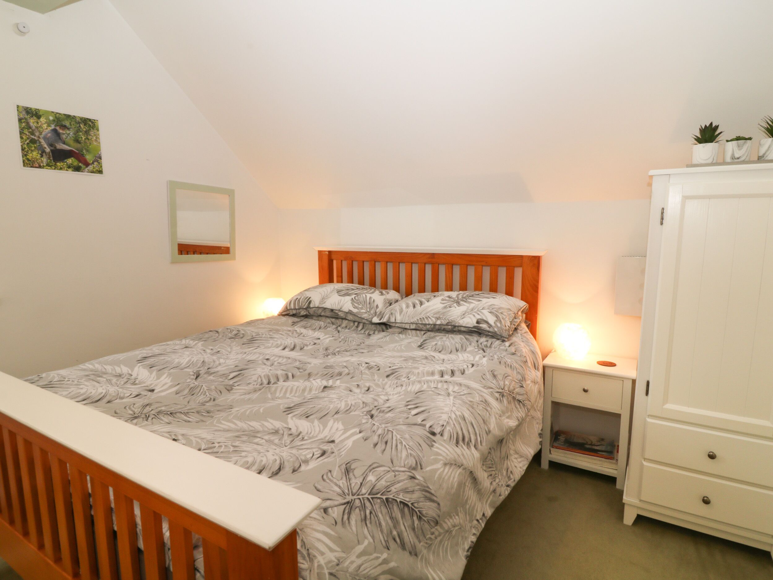 Un dormitorio con cama, mesitas de noche, armario y un cuadro en la pared.