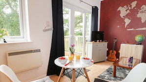 Una habitación con una mesa de comedor, dos sillas, un televisor, una guitarra y un globo terráqueo sobre un mueble.