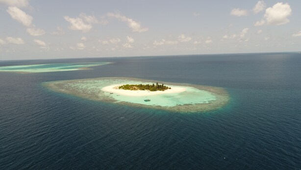 Eine Luftaufnahme einer kleinen Insel mit klarem türkisblauem Wasser und einem Sandstrand.
