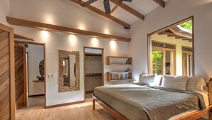 Un dormitorio con cama de madera, un espejo grande y una viga de techo de madera.