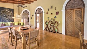 Un comedor con una mesa y sillas de madera, un mural de Buda y una estantería de madera.