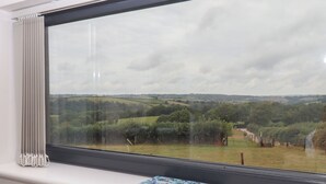 Une fenêtre donnant sur un paysage rural, un radiateur et un carnet posé sur le rebord de la fenêtre.