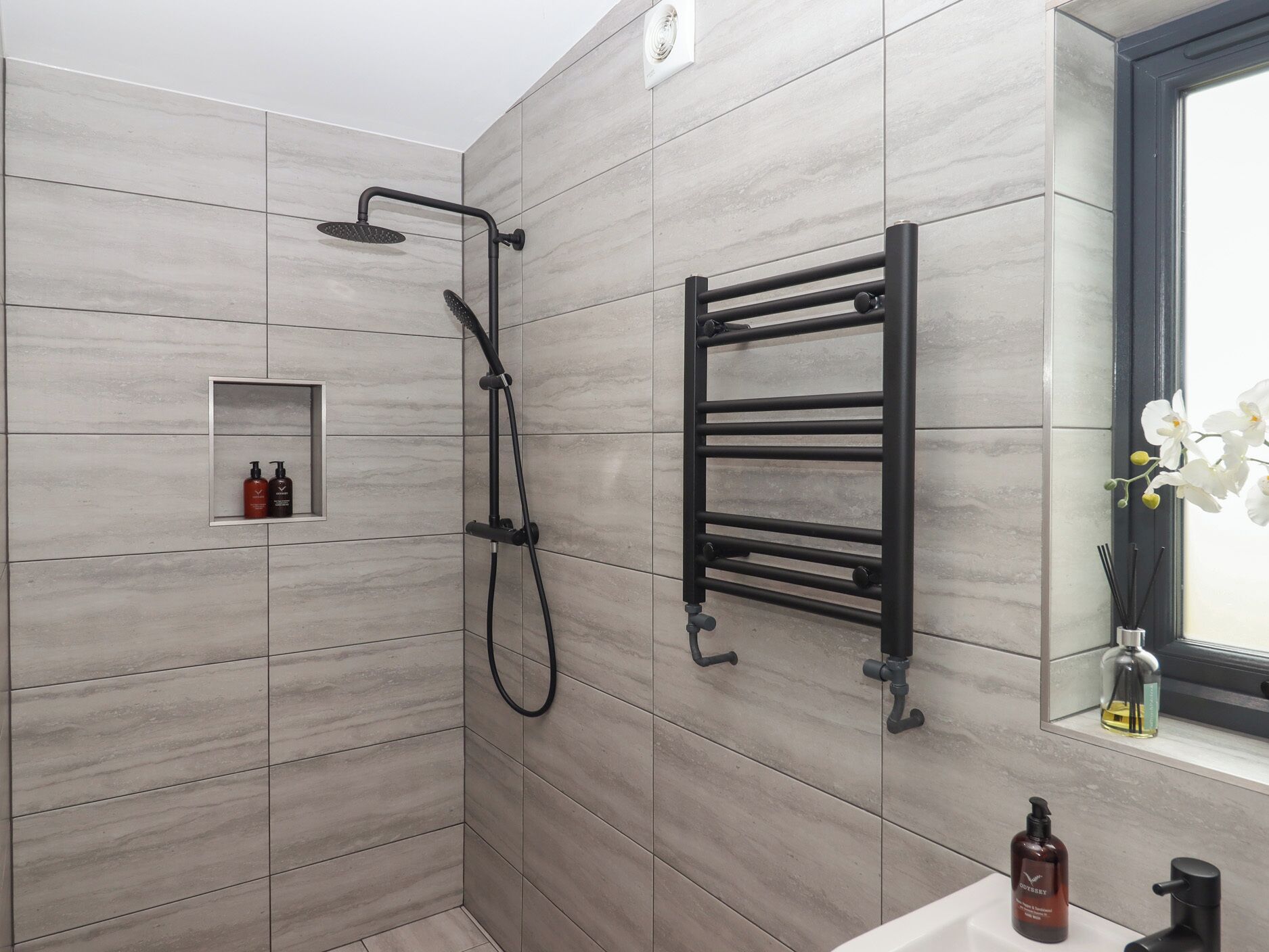 Un baño moderno con ducha, perchero y un estante pequeño con artículos de aseo.