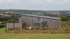 A wooden building with a flat roof, surrounded by a grassy area and a fence. - The Cadeleigh (Tiverton)
