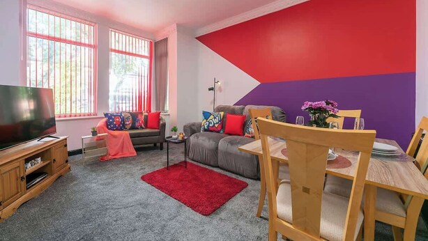 Ein Wohnzimmer mit Fernseher, Sofa und Esstisch.
