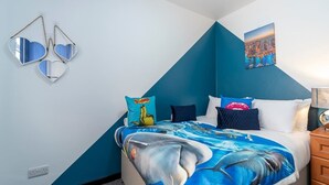 Ein Schlafzimmer mit einem Bett, Kissen, einem Wandspiegel und einem Stadtbild.