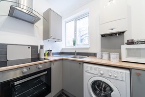 Eine kompakte Küche mit integriertem Backofen, Waschmaschine und Mikrowelle.