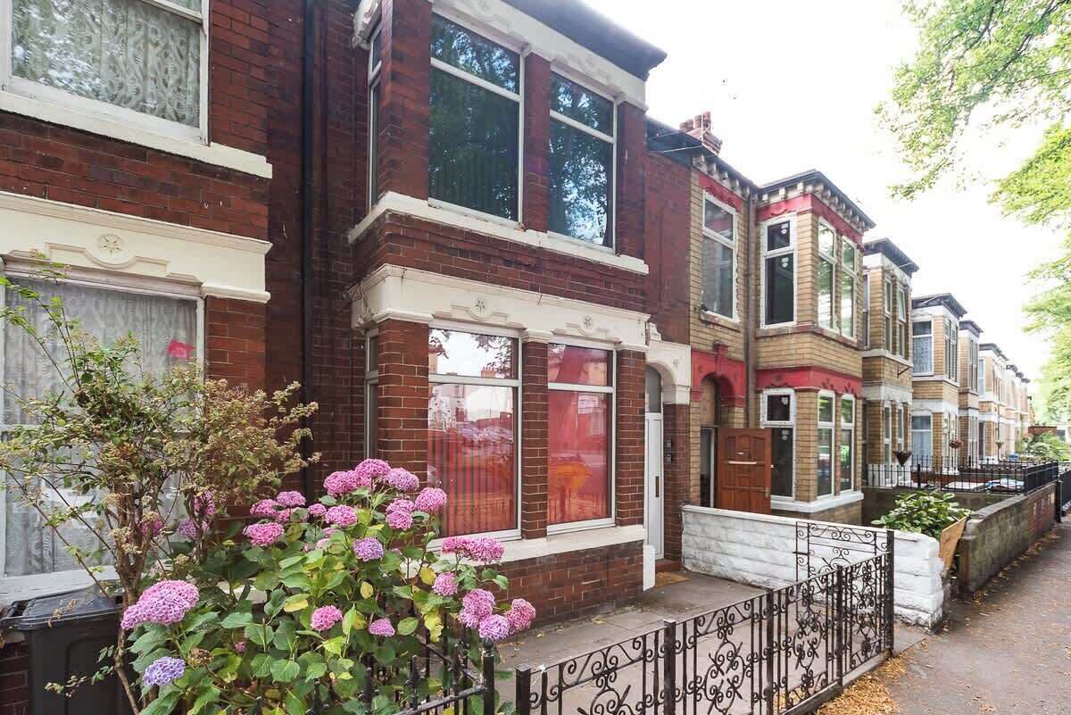 A row of terraced houses with brick facades, bay windows, and a small garden with hydrangea flowers.