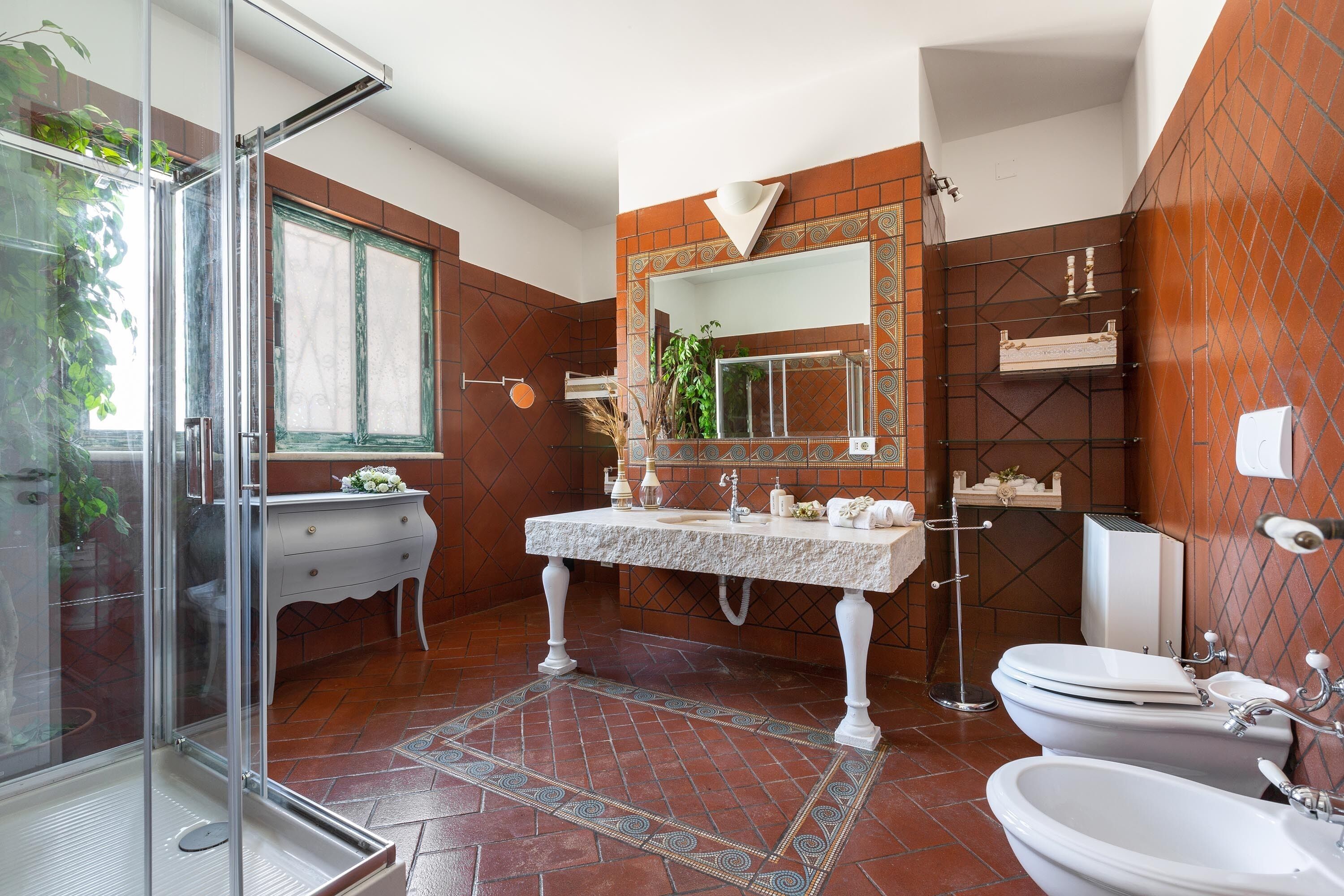 A modern bathroom with a glass shower enclosure, a white vanity, a large mirror, and a tiled floor.