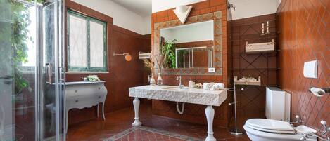A modern bathroom with a glass shower enclosure, a white vanity, a large mirror, and a tiled floor.