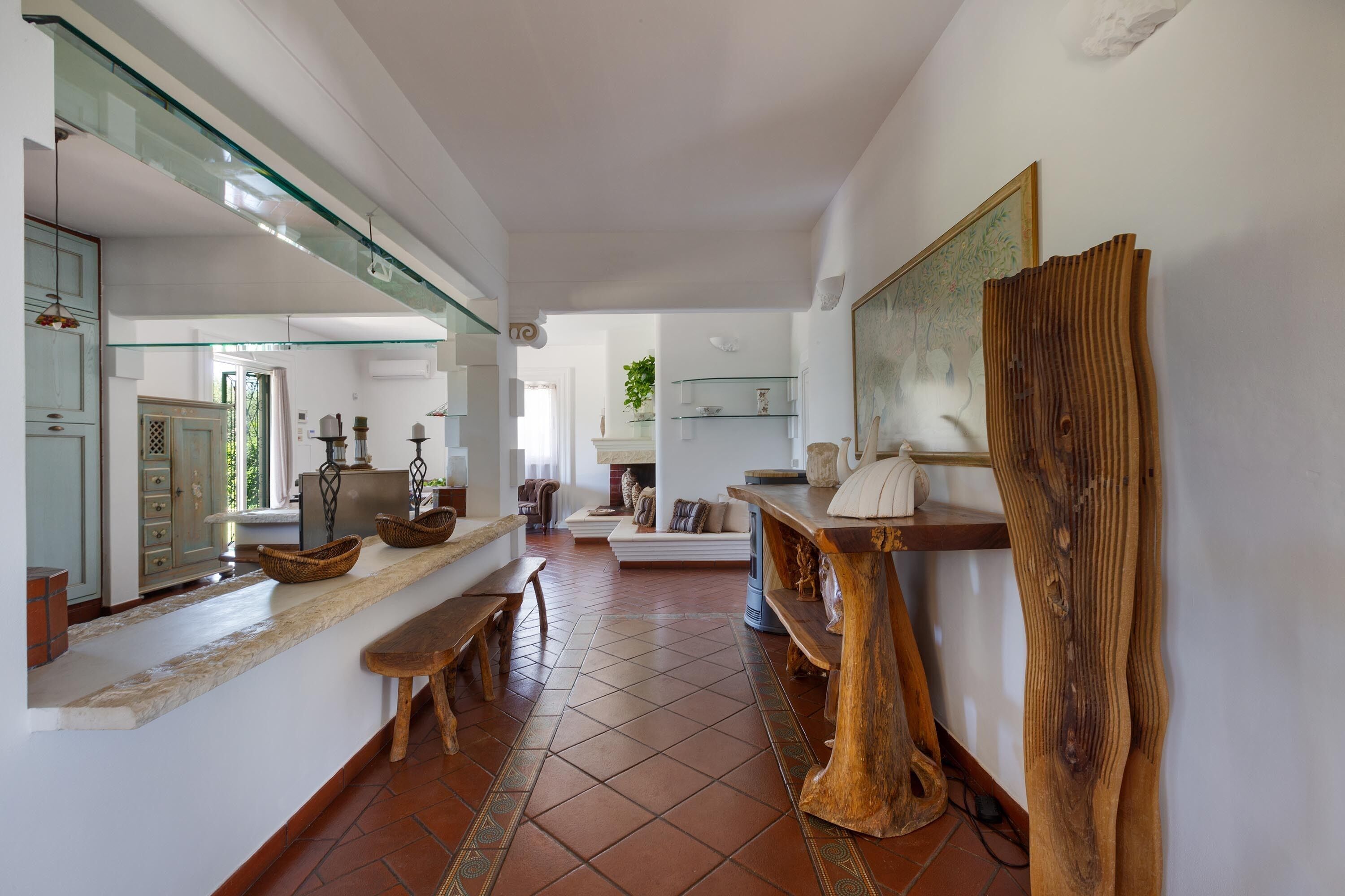 A spacious living area with a long wooden bench, a glass railing, and a rustic wooden table.
