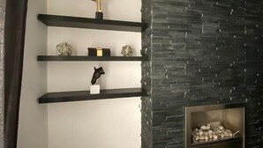 Ein modernes Interieur mit Kamin aus Stein, integrierten Regalen mit Dekoration und minimalistischem Design.