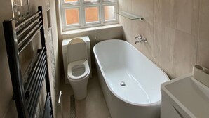 Ein Badezimmer mit Badewanne, Toilette und Fenster.