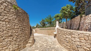 A stone pathway leading to a building with a stone wall on one side and a fence on the other. - Villa Lodrea by Perle di Puglia (Torre Vado)