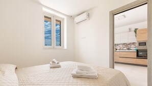 Un dormitorio con cama, ventana y vistas a una cocina moderna.