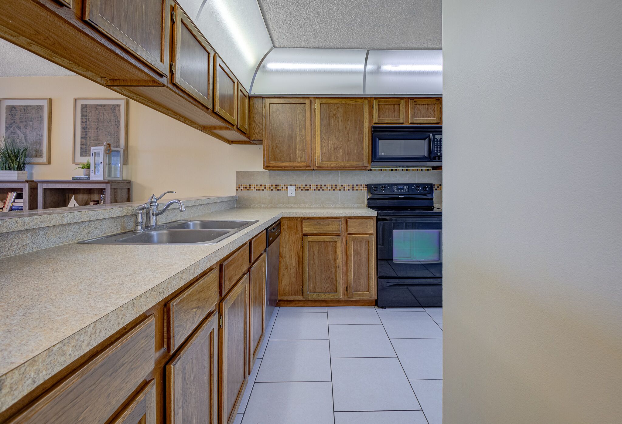 A kitchen with wooden cabinets, a granite countertop, a stainless steel sink, a microwave, and a stove.