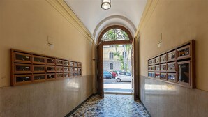 Un couloir doté d’un sol carrelé, de vitrines en bois de part et d’autre, et d’une porte en arc donnant sur l’extérieur.