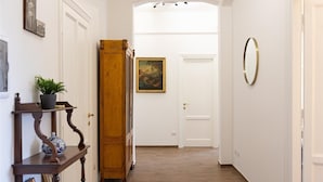 Ein Korridor mit Holzboden, einem großen Holzschrank, einem Blumentopf und einem gerahmten Bild auf einem Regal.
