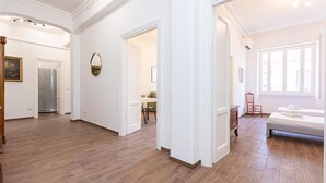 Ein geräumiges Zimmer mit Holzboden, einem Bett, einem Sessel und einem Schreibtisch.