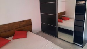 A bedroom with a bed, a wooden headboard, a wardrobe with a mirror, and red pillows. - Bright apartment with large balcony (marseille)