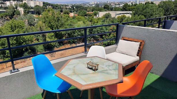 A balcony with a table and chairs, a view of a cityscape, and a railing. - Bright apartment with large balcony (marseille)