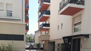 A courtyard with a building featuring multiple balconies and a gated entrance. - Bright apartment with large balcony (marseille)