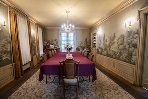 A formal dining room with a long table, chairs, and a chandelier.