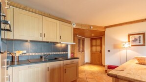 A kitchen with wooden cabinets, a sink, and a countertop. There is a door leading to another room. - 50m from ski slopes, floor -2, view valley, swimming pool, balcony, tv, ski locker, 76m², Les Arcs (Bourg-Saint-Maurice)