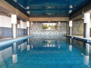 Swimmers can enjoy a refreshing dip in the pool surrounded by columns and a scenic view.
