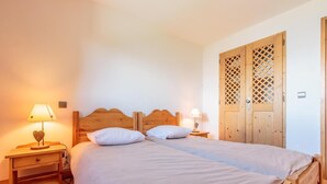 A double bed with a wooden headboard, two bedside tables with lamps, and a wooden wardrobe with a lattice design. - 50m from ski slopes, floor -2, view valley, swimming pool, balcony, tv, ski locker, 76m², Les Arcs (Bourg-Saint-Maurice)