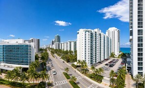 A high-rise hotel with multiple floors, a parking lot, and a clear view of the ocean.