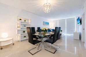 A modern dining area with a glass table, black chairs, and a chandelier. - Wake up over the Atlantic | Private beach access, pool & gym (Hollywood)