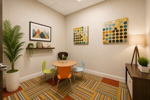 Una sala de reuniones moderna con una mesa redonda, sillas coloridas y arte abstracto en la pared.