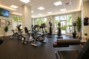 Un gimnasio con equipo de ejercicio variado, ventanas amplias y decoración inspiradora en las paredes.