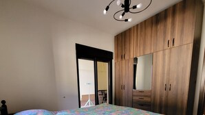 A bedroom with a bed, a wooden wardrobe, and a ceiling light fixture. - Sweet Home Apartment (Batroun)