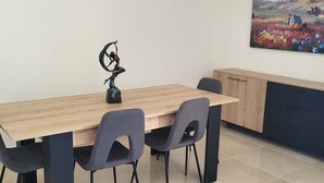 A dining area with a wooden table, four chairs, and a decorative sculpture. - Sweet Home Apartment (Batroun)