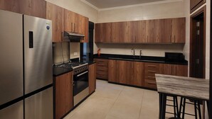 A modern kitchen with wooden cabinets, stainless steel appliances, and a black countertop. - Sweet Home Apartment (Batroun)