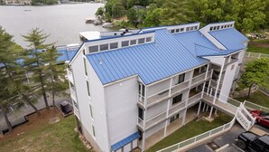 Un edificio de varios pisos con techo azul, balcones y vista a un lago.