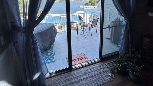 Una habitación con vistas a un muelle y al agua, un pequeño rincón de descanso con sillas y una mesa, y suelo de madera.