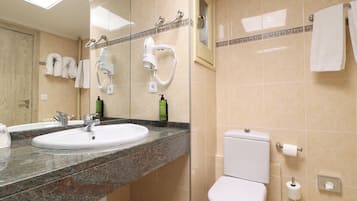 Een badkamer met een wastafel, spiegel, haardroger en toilet.