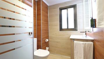 Een moderne badkamer met een houten wand, een toilet, een wastafel en een raam.