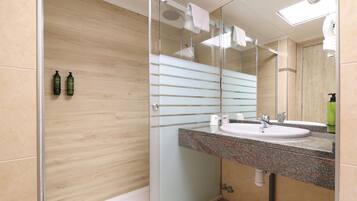 Une salle de bain moderne avec une douche à parois de verre, un lavabo sur un plan de travail en granit et un grand miroir.