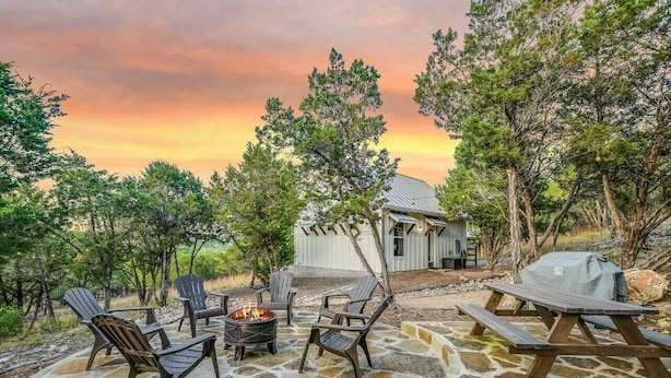 Un patio esterno con poltrone Adirondack, un braciere e un tavolo da picnic.