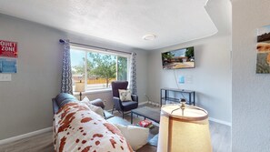 A cozy living room with a sofa, armchair, and a TV mounted on the wall.