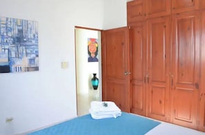 Une chambre à coucher avec un lit, une armoire en bois, un tableau accroché au mur et un vase.