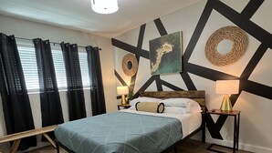 Une chambre à coucher moderne avec un lit, une table de chevet, une lampe et un mur orné de motifs géométriques.
