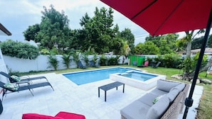 Un jardin avec une piscine, du mobilier d’extérieur et une pergola.