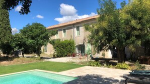 Zona de piscina amb una piscina nítida, paviment de pedra i vegetació al voltant.